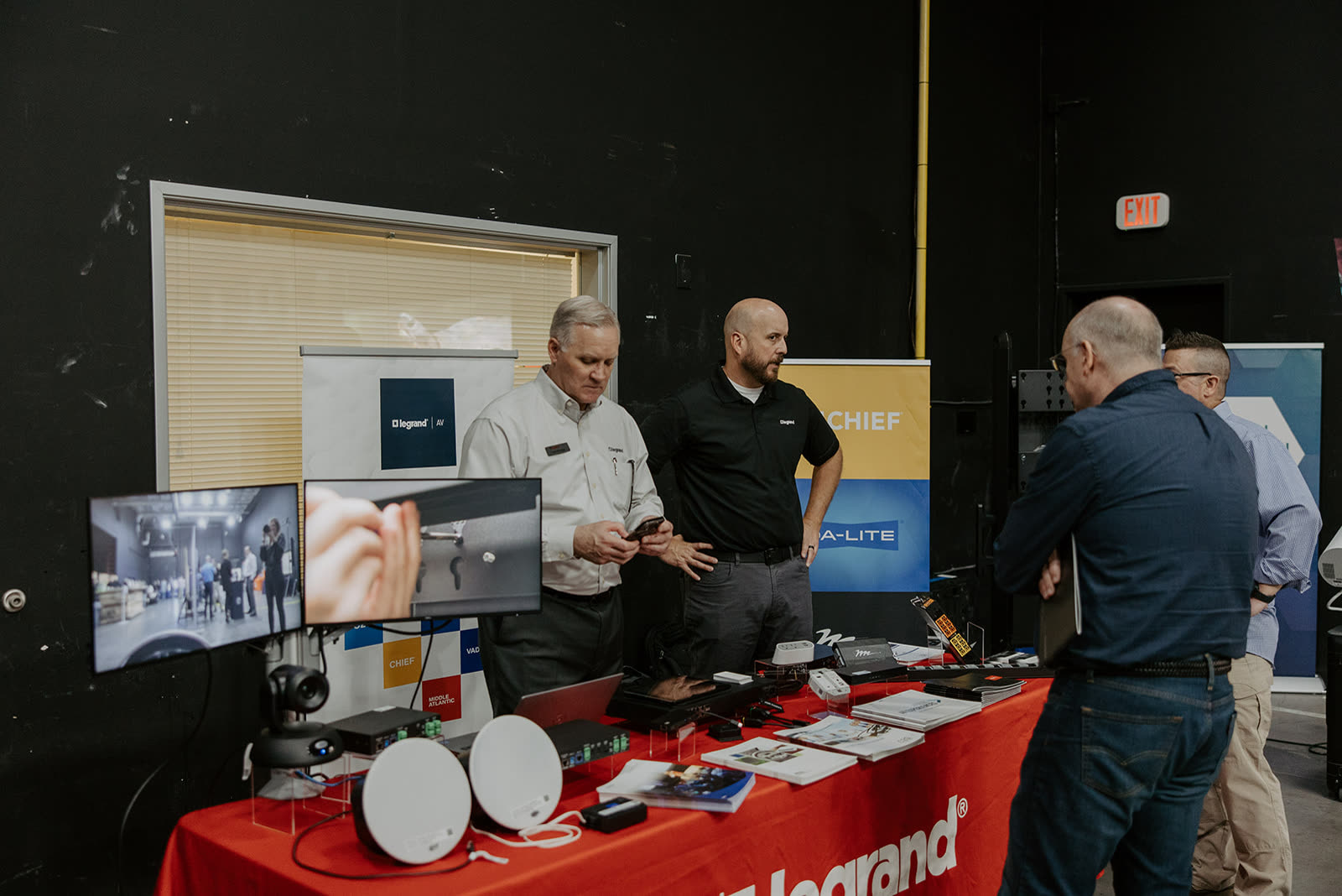 A demo table loaded with gear in front of a video wall